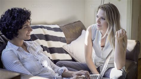Caucasian Lesbian Couple Talking On Sofa 11018056318 の写真素材・イラスト素材｜アマナイメージズ