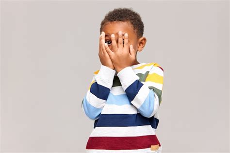 Free Photo Frightened Dark Skinned Little Boy Covering Face With Both
