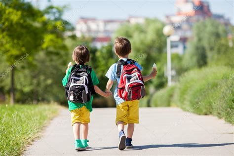 Two Adorable Boys In Colorful Clothes And Backpacks Walking Awa Stock