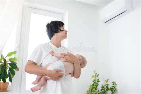 Mother Standing Picks Up Baby Near The Conditioner Stock Image Image