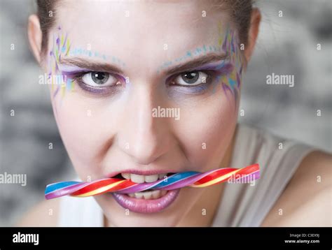 Portait Of Face Painted Young Woman Holding Colorful Candy In Her Teeth