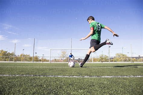 Football Player Shooting The Ball On Football Field Stock Photo