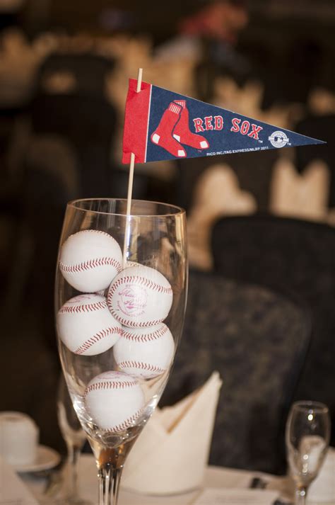 a glass filled with baseballs on top of a table next to a wine glass