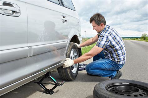 Man With Jack Changing A Spare Tire Of Car Stock Photo Image Of Driver Manual