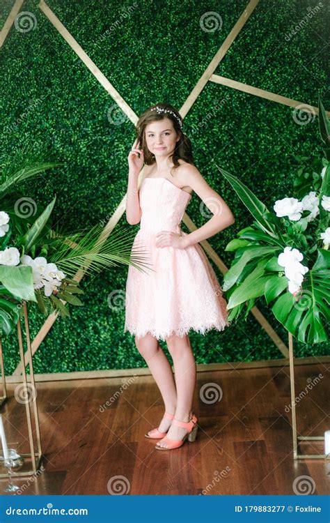 Attractive Young Girl In A Romantic Pink Dress Among Tropical Greenery And White Orchids Roses