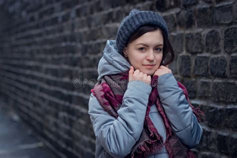 Sad Girl Stands Near A Brick Wall In Jacket Hat And Scarf Stock Image