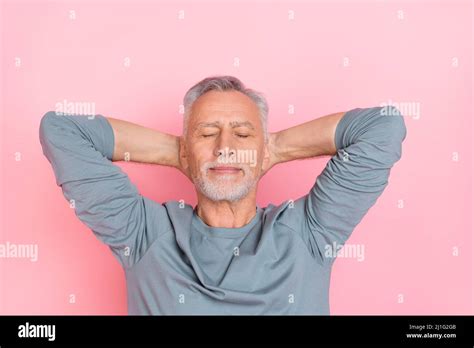 Foto de divertido hombre jubilado de ensueño usar camisa gris brazos detrás de la cabeza ojos