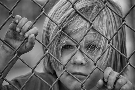 Black And White Photo Of A Child Looking Through The Bars Free Image