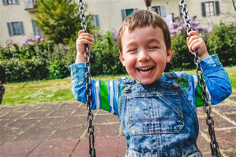 Preschooler Boy Having Fun On A Swing At The Playground By Stocksy