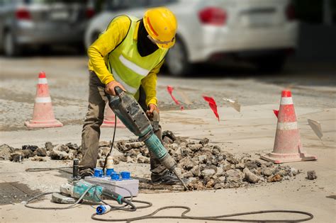 Worker Drilling Concrete Driveway With Jackhammerman Repairing Road Surface With Heavy Duty