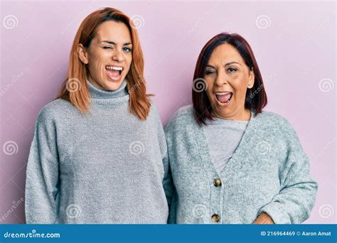 Latin Mother And Daughter Wearing Casual Clothes Winking Looking At The Camera With Expression
