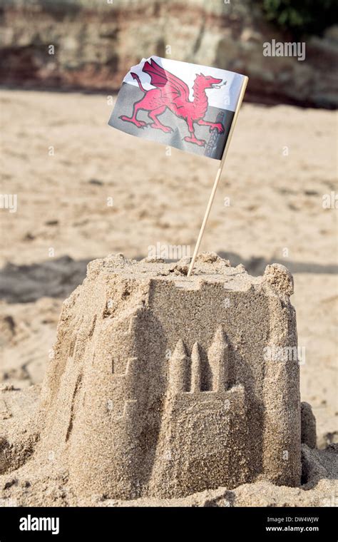 A Sand Castle On A Sandy Beach Topped With The Welsh National Flag