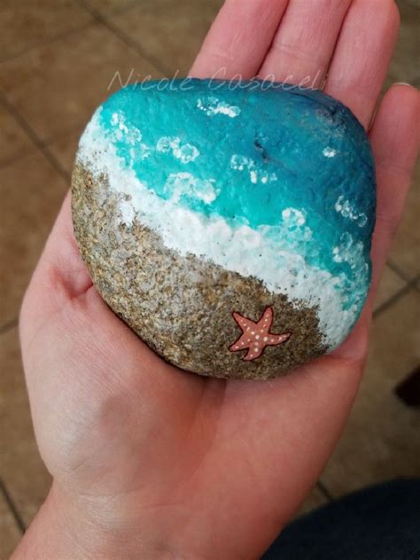 A Hand Holding A Rock With A Starfish Painted On It And Sand In The Middle