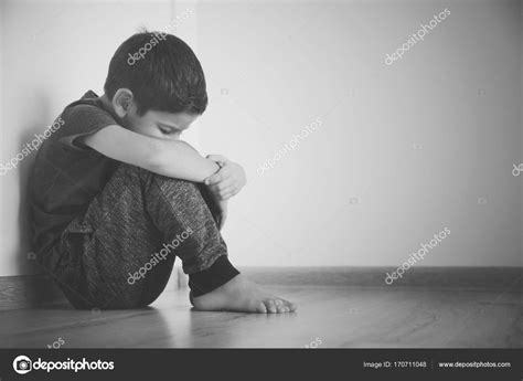 Little Sad Boy Sitting On Floor At Home Stock Photo By ©belchonock