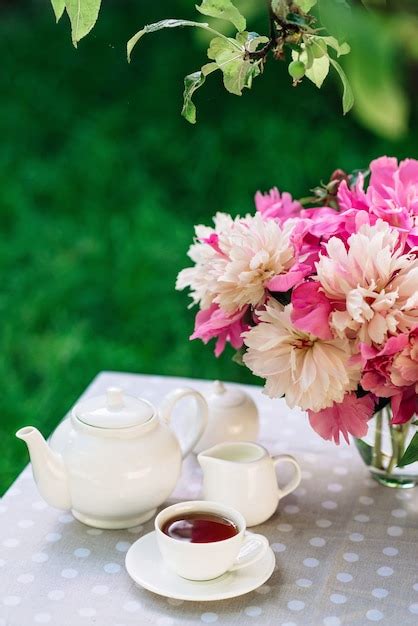 Premium Photo A Vase Of Peonies Flowers Near A Cup Of Tea