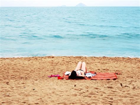Premium Photo Woman In Bikini Swimsuit Lie Down On Red Mat For Sunbath And Relax On Sand Blue