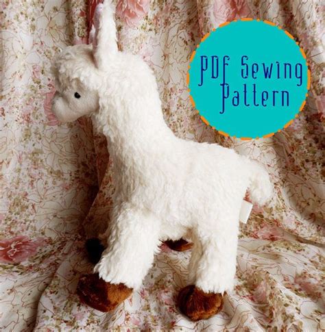 A White Stuffed Llama Sitting On Top Of A Floral Cloth Covered Bed