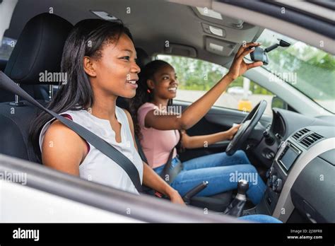Young Black Teenage Driver Seated In Her New Car With Her Mother Stock
