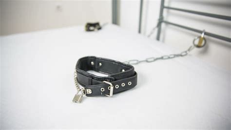 pad lock with chain on bed with leather collar bondage and dominance sexual play in bedroom
