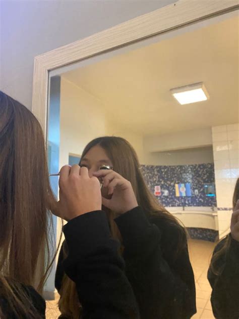 Two Women Standing In Front Of A Mirror While Brushing Their Teeth