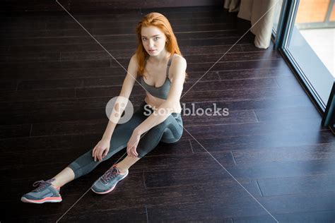 Portrait Of A Fitness Redhead Woman Sitting On The Floor And Looking At Camera Royalty Free