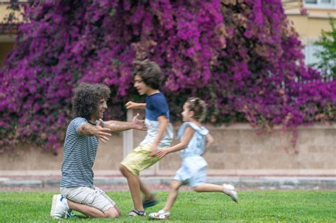Photo Of Son And Daughter Running Toward Father In Public Park Stock