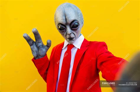 Portrait Of Man Wearing Alien Costume And Bright Red Suit Reaching