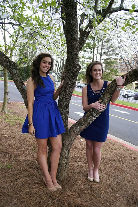 Two Women Standing Next To Each Other Near A Tree