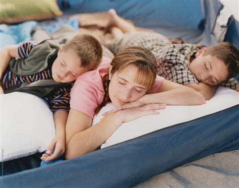 Mother And Sons Sleeping Together In Camping Tent By Rialto Images