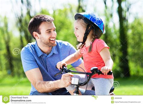 Muchacha Que Aprende Montar Una Bici Con Su Padre Foto De Archivo