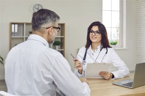 Young Female Doctor With Clipboard Asking Patient Questions During
