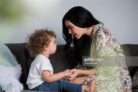 Caucasian Mother Sitting On Sofa Holding Hands And Talking With Son