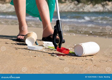 Close Up Of Person Collecting Plastic Waste From Polluted Beach Using