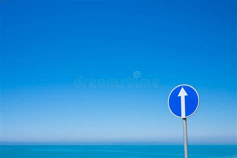 Circle Road Sign With White Arrow On Blue Sky Background Stock Image
