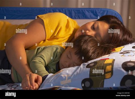 A Mother Laying In The Bed Next To Her Sleeping Son Stock Photo Alamy