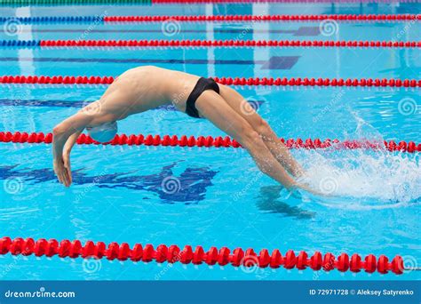 Giovane Nuotatore Muscolare Che Salta Dal Blocchetto Iniziare In Una Piscina Fotografia Stock