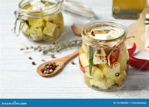 Jar With Feta Cheese Marinated In Oil On White Wooden Table Stock Photo