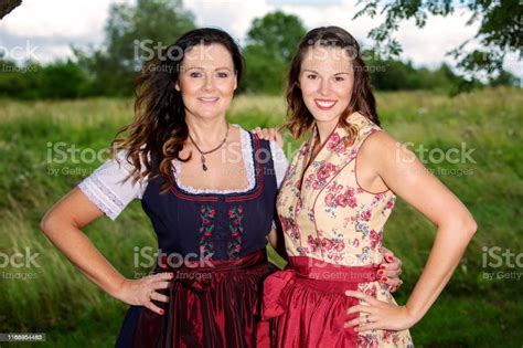 Portrait Of Two Women In Bavarian Dirndl Standing Outdoors Stock Photo