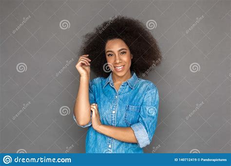 Freestyle Mulatto Woman Standing Isolated On Grey Touching Curl Smiling Playful Stock Image
