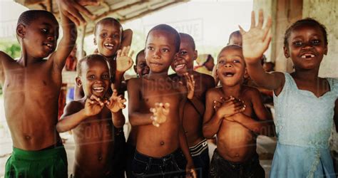 A Group Of African Children Laughing Jumping And Waving In Rural Area
