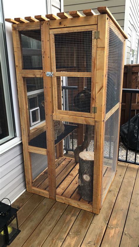 A Large Bird Cage Sitting On Top Of A Wooden Deck Next To A Building
