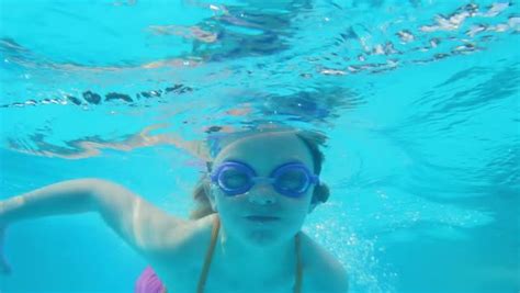 A Young Girl Swimming Underwater In Pool Goes Away From The Camera