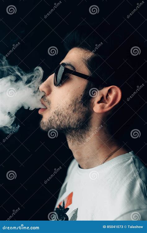 Young Cool Guy In Sunglasses Exhales A Cloud Of Smoke Vertical Studio