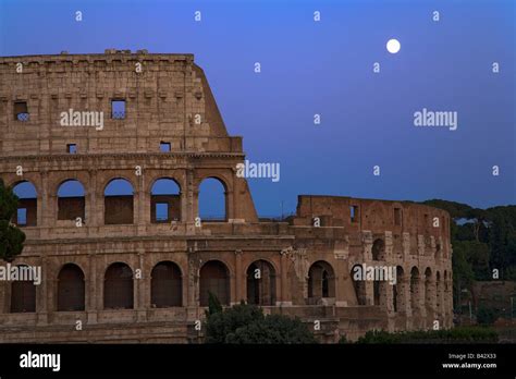 Full Moon Rising Over The Colosseum Or Roman Coliseum At Dusk