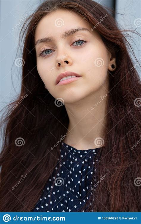 Fashionable Long Haired Brunette Woman Posing Near The Metal Shutters