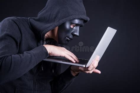 Hooded Hacker Anonymous Mask Using Laptop To Steal Data Stock Photos