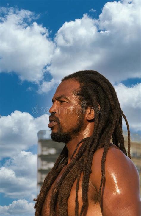 Handsome Shirtless Hispanic Man With Dreads Standing Outdoors Against A