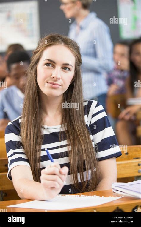 Portrait Of Female Student Sitting At Desk In Classroom Stock Photo