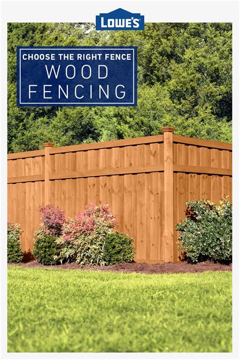 A Wooden Fence In Front Of Some Bushes And Trees With A Blue Sign That