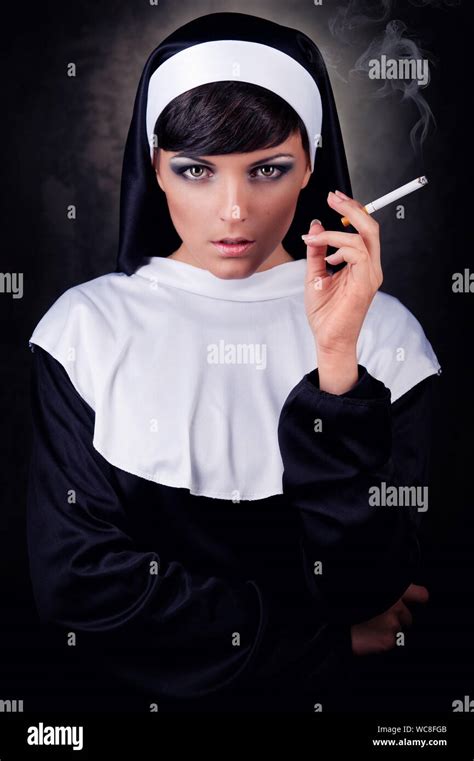Portrait Of Nun Smoking While Standing Against Black Background Stock